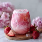 Refreshing pink drink made with strawberries and coconut milk in a glass with ice